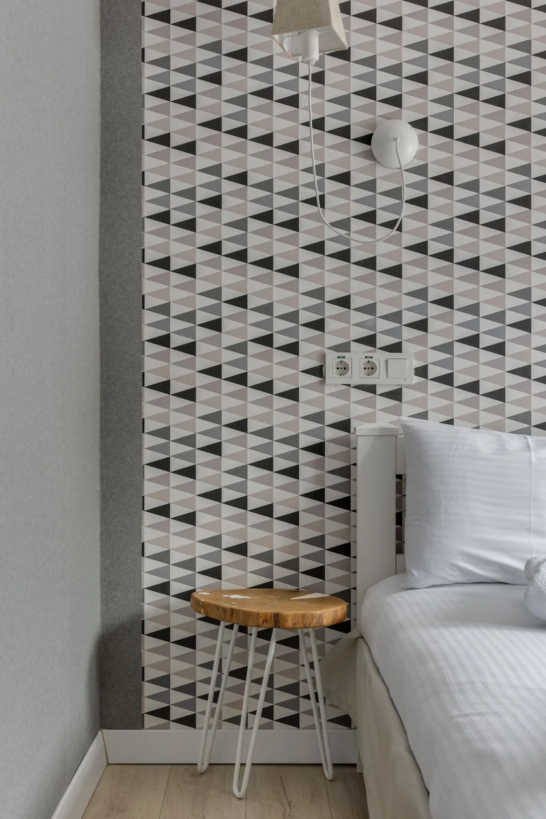 Bedside accent wall finished with a crisp black-and-white geometric wallpaper